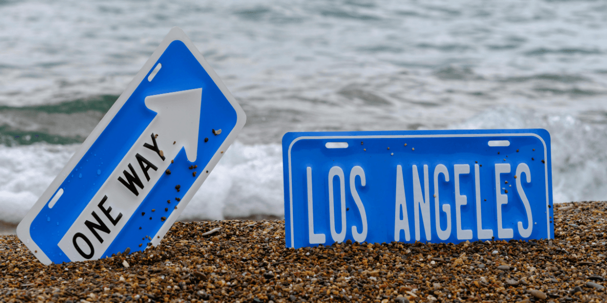 Two blue road signs on a sandy beach with ocean waves in the background
