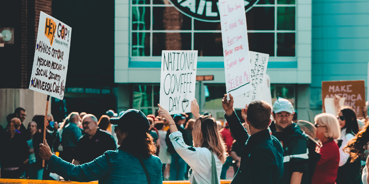 Crowd holding protest signs outside a building during a public demonstration