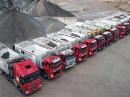 Fleet of MCS automated silo trucks lined up at a construction materials production site.