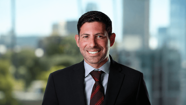 Smiling man in a suit with a blurred city background