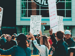 Crowd holding protest signs outside a building during a public demonstration