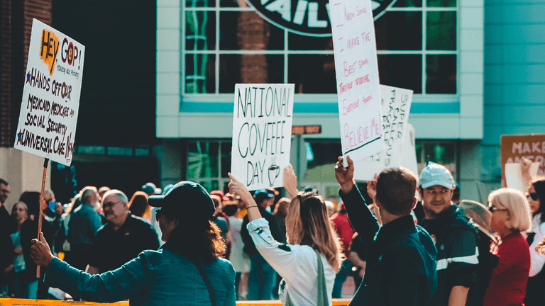 Crowd holding protest signs outside a building during a public demonstration