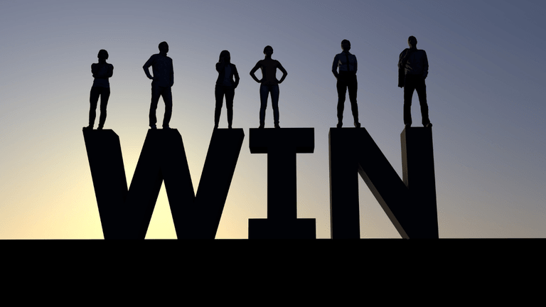 Silhouetted figures stand on large letters spelling "WIN" against a sunset backdrop