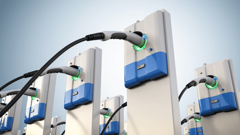 Multiple electric vehicle charging stations with plugged cables and illuminated indicators