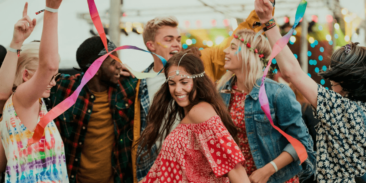 Group of people dancing joyfully at a festive outdoor event with colorful decorations