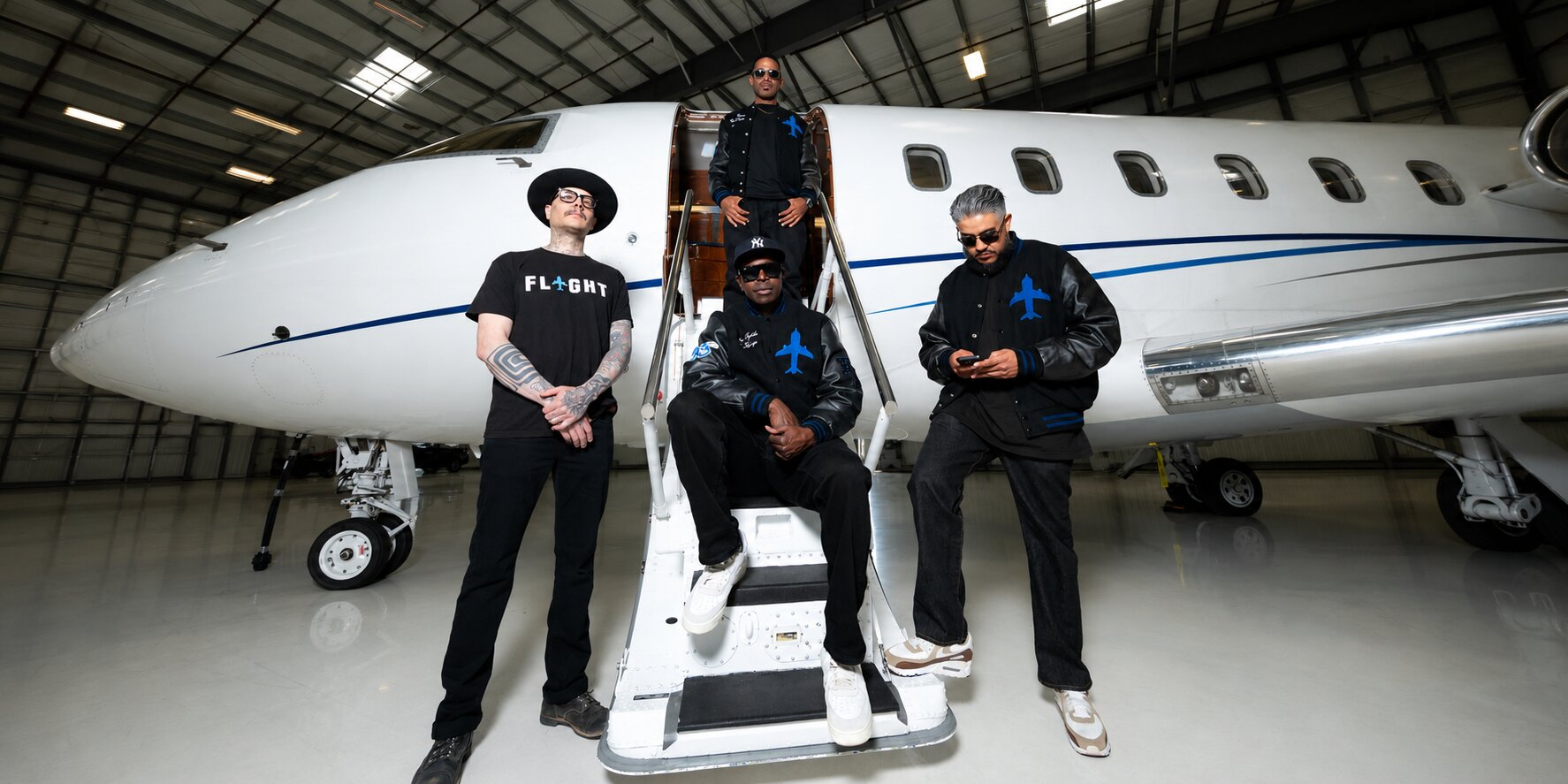 Flight Bernal Heights team posing on private jet stairs inside an aircraft hangar.