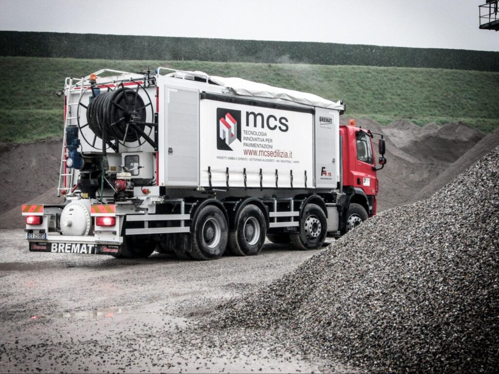 MCS automated silo truck transporting dry flooring materials at a construction aggregate facility.